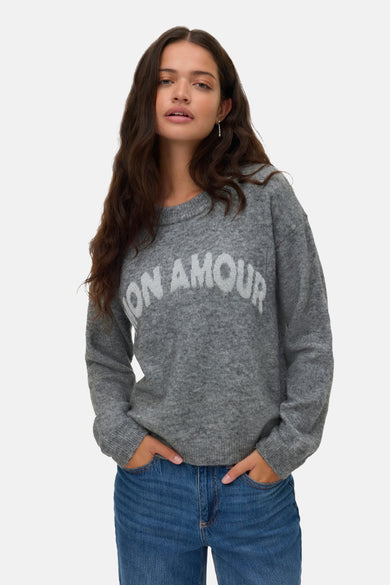 Sweat-shirt gris avec col rond de VERO MODA, avec le texte "Mon Amour" dessus, associé à un jean bleu.