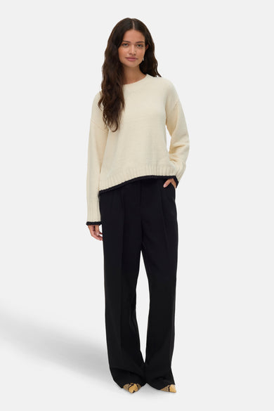 T-shirt écru avec col rond de VERO MODA, fini avec des détails sombres et associé à un pantalon noir.