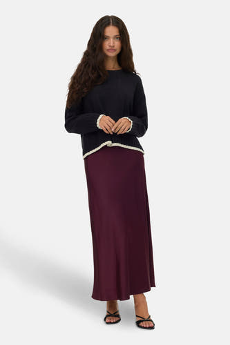 Zwarte trui met ronde hals van VERO MODA®, afgewerkt met geribbelde details bij de mouwen en zoom, gecombineerd met een lange bordeauxrode rok en zwarte sandalen.