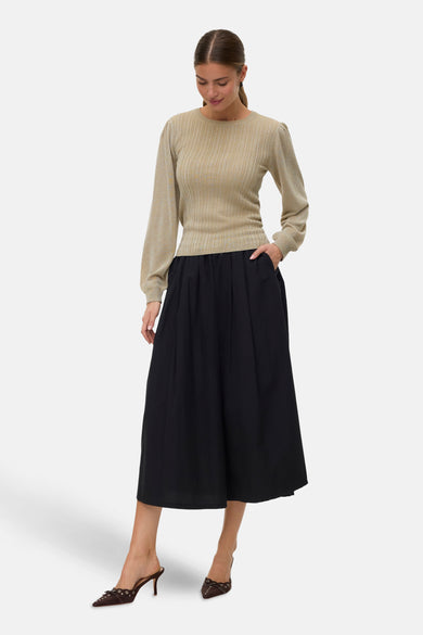 T-shirt vert avec col rond de VERO MODA, porté avec une jupe midi noire et des baskets marrons.