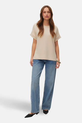 Ecru T-shirt met korte mouwen van VERO MODA, gedragen met wijde jeans en zwarte schoenen.