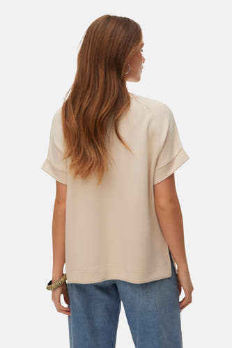 T-shirt écru à manches courtes de VERO MODA, vu de dos avec cheveux détachés et jeans.