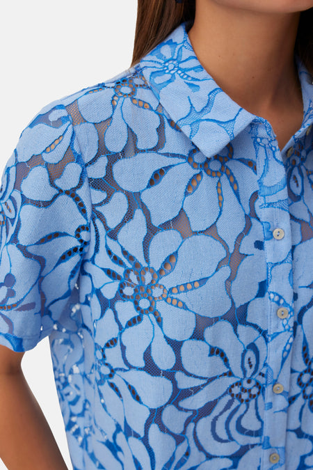 Chemise bleue à manches courtes de VERO MODA, avec un motif de dentelle florale détaillé et des boutons visibles.