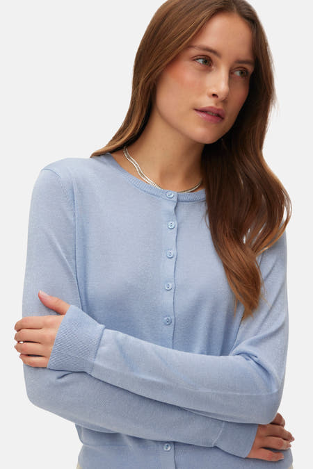 Cardigan bleu de VERO MODA®, vu de l'arrière, porté avec une jupe crème.