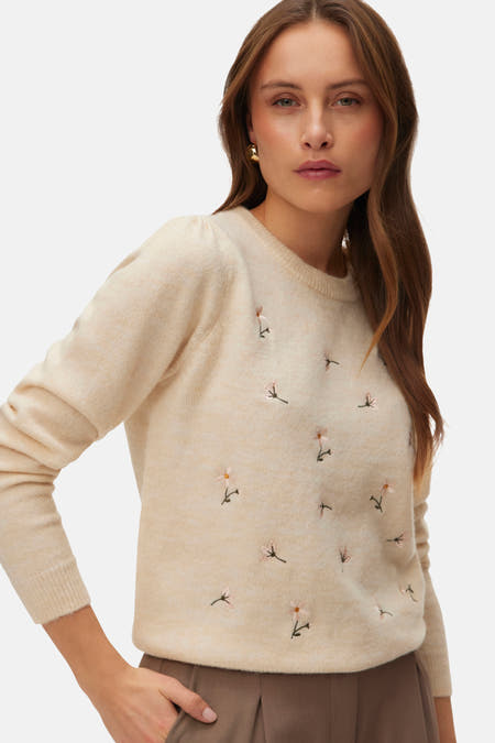 Ecru trui met ronde hals van VERO MODA®, voorzien van geborduurde bloemen en gedragen met een bruine broek.
