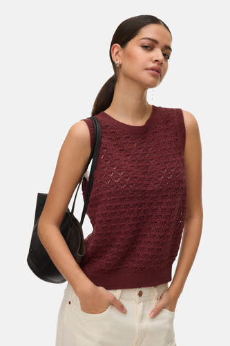 Débardeur de couleur brique de VERO MODA, avec un motif ajouré, combiné avec un pantalon de couleur crème et un sac à main noir.