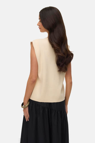 Cardigan écru de VERO MODA, avec une jupe noire et un bracelet doré.