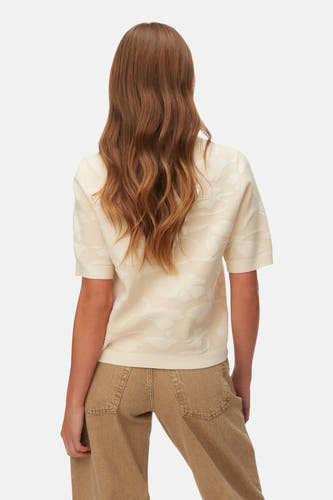 Pull écru à col rond de VERO MODA, avec motif floral subtil et manches courtes, vu de dos.