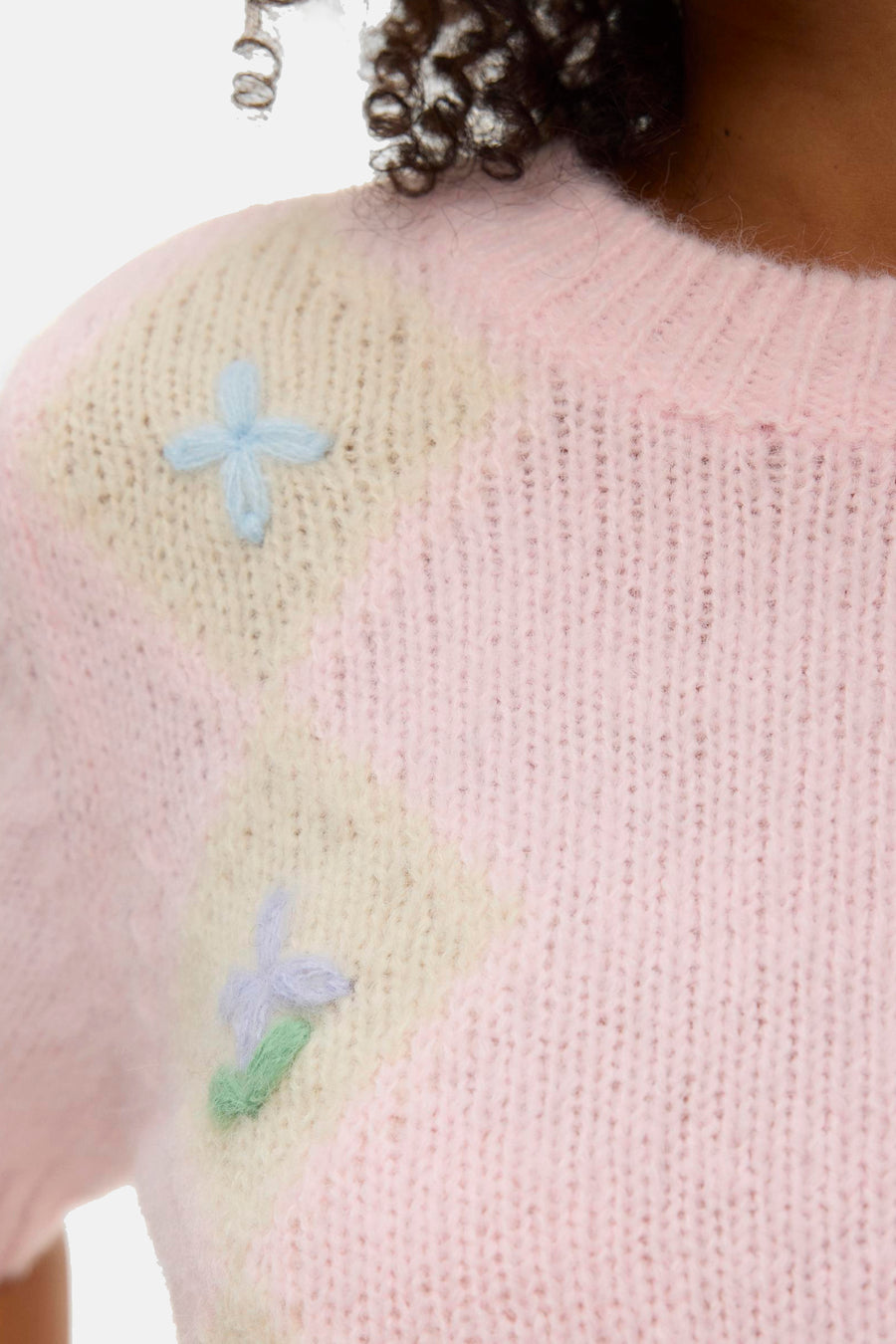 Pull rose à col rond de Vero Moda, avec des accents pastel et des détails de fleurs brodées sur l'épaule.