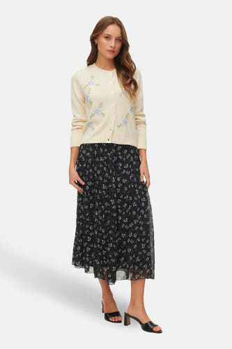 Ecru gilet van VERO MODA® met subtiele geborduurde bloemen, gedragen met een zwarte bloemenrok en hakken.
