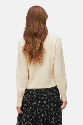 Ecru gilet van VERO MODA, met lange mouwen en een zwarte rok met bloemenprint.
