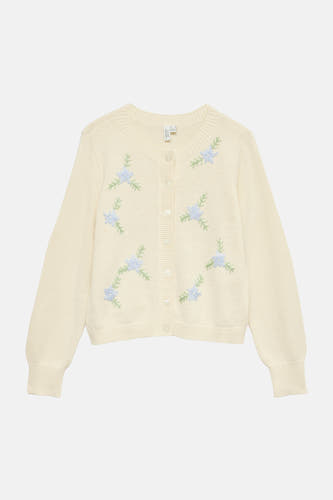Gilet de couleur écru de Vero Moda, avec des fleurs bleues brodées et des manches longues.