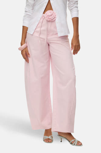 Jeans de couleur rose de VERO MODA, avec jambes larges et poches arrière, combinés avec un chemisier blanc et des talons.