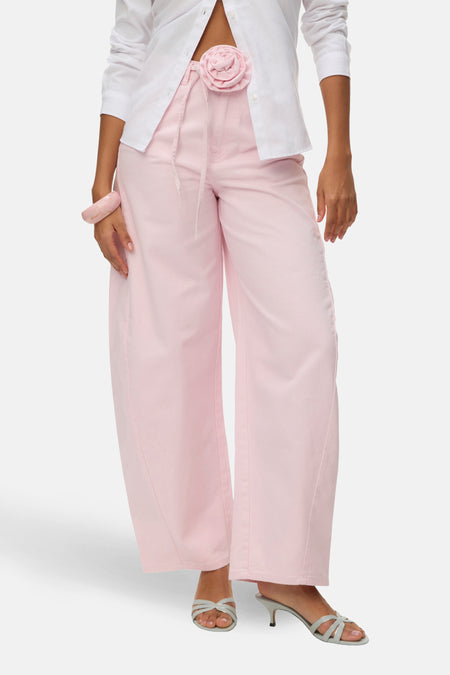 Roze gekleurde jeans van Vero Moda, met wijde pijpen, een stoffen bloem detail en een roze armband.