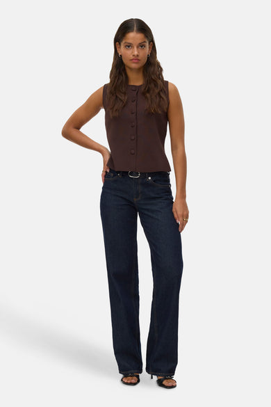 Gilet marron de VERO MODA®, avec fermeture à boutons, associé à un jeans foncé et des bottes noires.