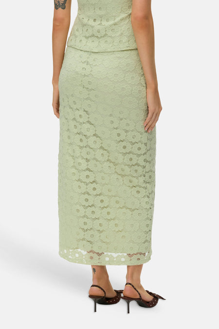 Groene lange rok van VERO MODA, met bloemenkant, in rugweergave, gedragen met bruine hakken met stippen.