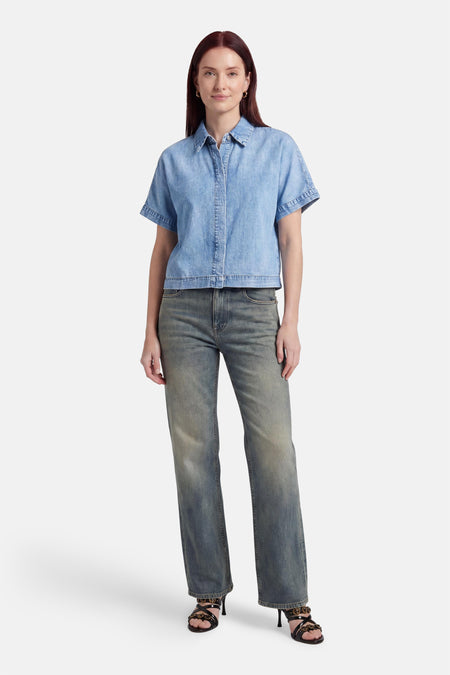 Chemisier en denim bleu clair à manches courtes de VERO MODA®, avec col classique et boutons, stylé avec un jean foncé.