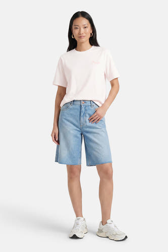 Witte korte mouw T-shirt van VERO MODA® met roze borduursel, gedragen met blauwe denim shorts en witte sneakers, front view.