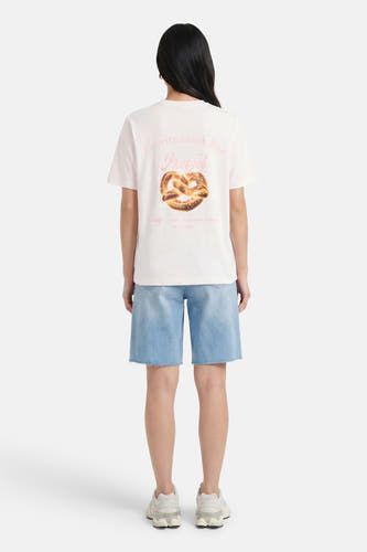Witte korte mouwen t-shirt met pretzel print van VERO MODA®, achterkant weergegeven, model draagt lichtblauwe denim shorts en witte sneakers