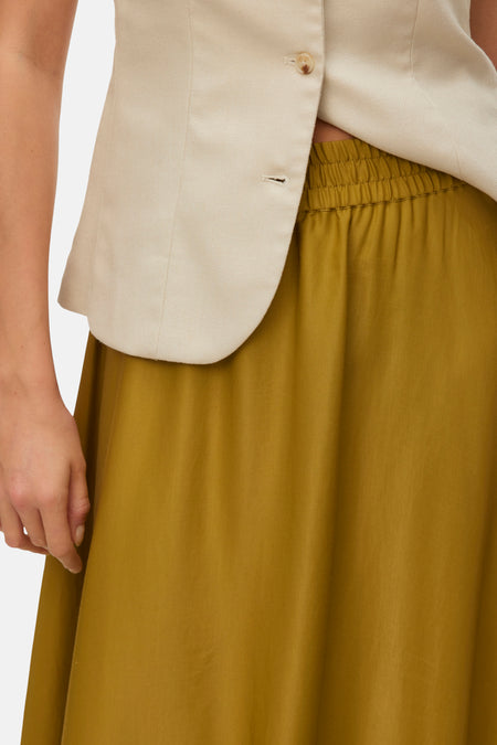 Jupe longue vert olive de VERO MODA avec taille élastique, combinée à un haut sans manches de couleur crème.