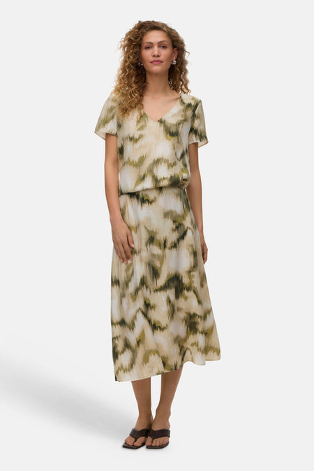 Chemisier multicolore à manches courtes de VERO MODA® avec imprimé abstrait vert-beige, porté avec une jupe assortie, dos côté.