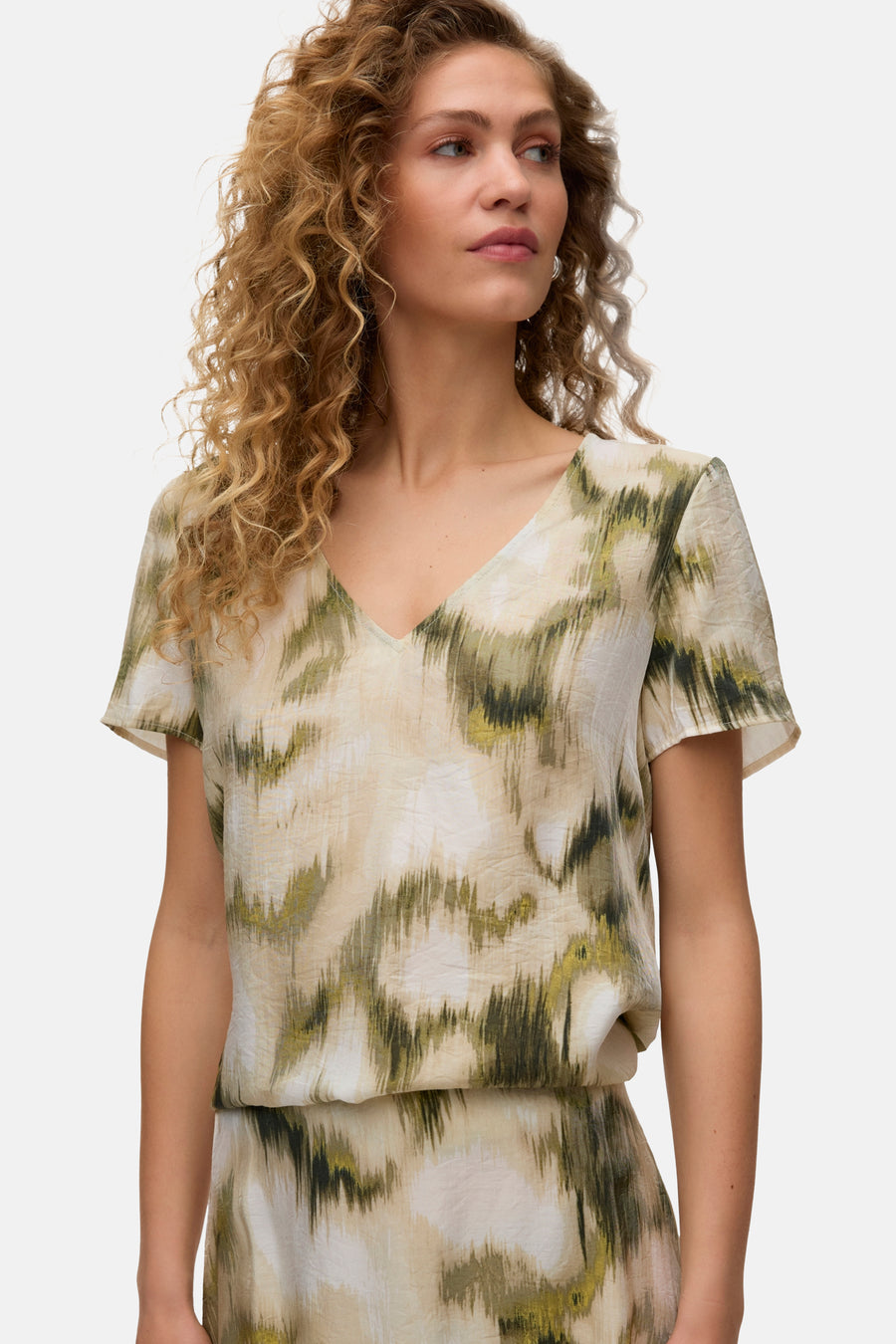 Chemisier multicolore à manches courtes de VERO MODA, avec imprimé abstrait en vert, beige et blanc, et un col en V.