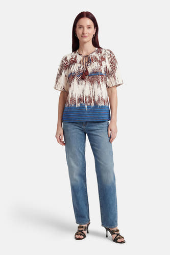 Multicolor blouse met korte mouwen van VERO MODA® met abstract patroon, strikhals met kwastjes, gecombineerd met jeans en sandalen.