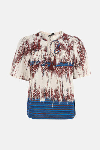 Chemisier multicolore à manches courtes de VERO MODA® avec des motifs abstraits et tribaux rouges et bleus, et des pompons au col.