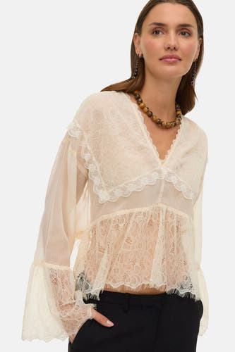 Blouse écru à longues manches de VERO MODA, avec des détails sur les bords et un col en V, associée à une jupe noire et une chaîne.