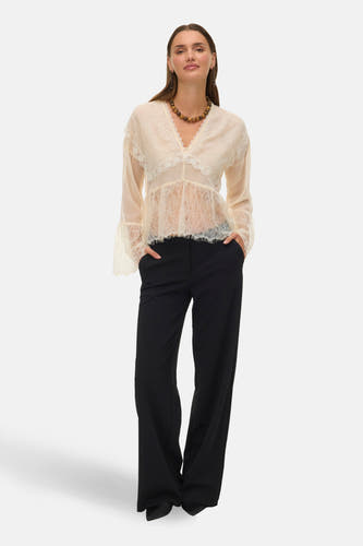 Ecru blouse met lange mouwen van VERO MODA, met kanten details en een V-hals, gecombineerd met een zwarte broek en ketting.
