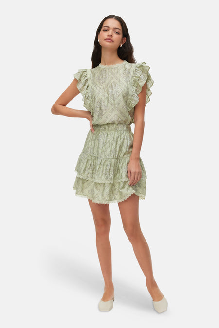 Groene blouse met korte mouwen van VERO MODA, met ruffles en wit patroon, onderdeel van een bijpassende jurk gedragen door een model.