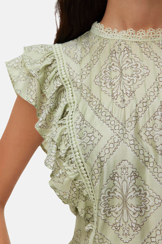 Chemisier vert clair à manches courtes de VERO MODA, avec volants, encolure en dentelle, passepoil à pois et motif à pois marron et blanc.