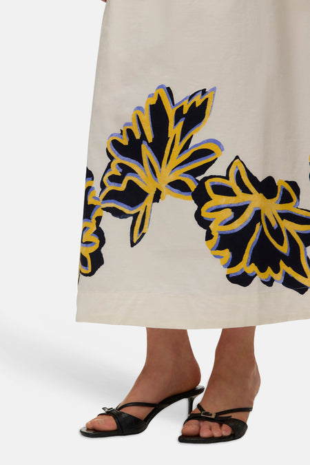 Jupe longue écru de VERO MODA avec motif floral abstrait en noir, jaune et lilas, portée avec des sandales noires à talons.