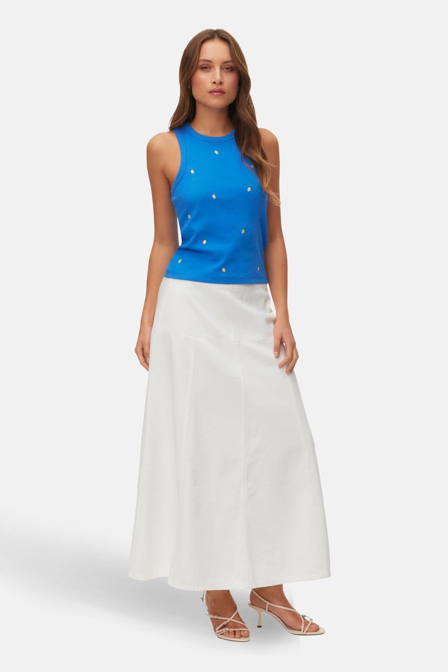 Blauwe singlet tanktop van Vero Moda, met geborduurde citroenmotieven, gecombineerd met een lange witte rok en hakken.
