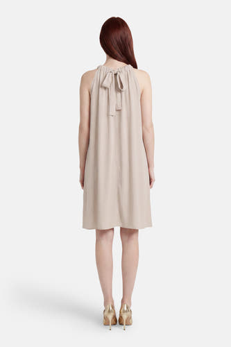 Beige mouwloos kleedje van VERO MODA® met striksluiting achter in de nek, getoond vanaf de achterzijde, met gouden hakken.