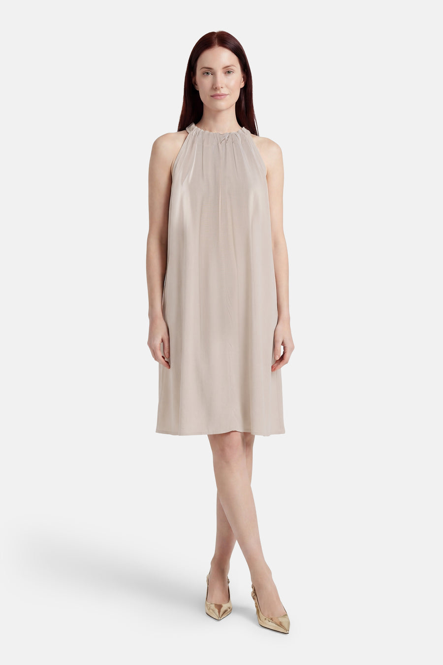 Robe beige sans manches de VERO MODA avec col licou plissé, porté avec des escarpins dorés.
