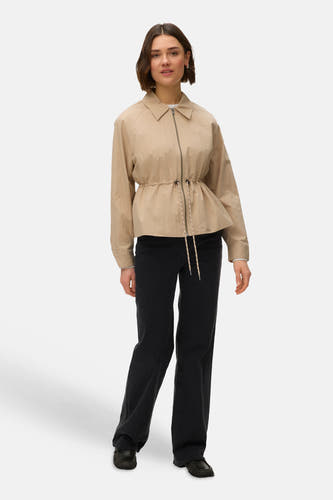 Beige korte jas van VERO MODA, met lange mouwen, trekkoord in de taille en zwarte jeans.