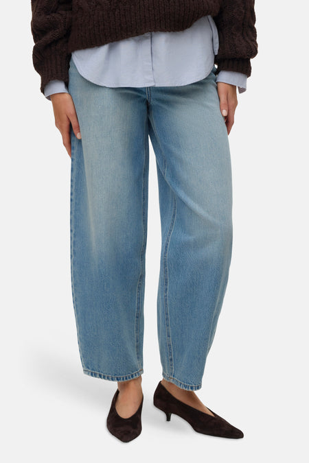 Jean bleu clair VERO MODA à jambes larges, grandes poches arrière et ourlets retroussés, porté avec un pull marron et des talons en daim, dos.