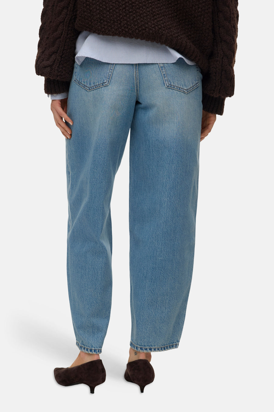 Lichte blauwe spijkerbroek van VERO MODA met wijde pijpen, grote achterzakken en opgerolde zomen, gedragen met een bruine trui en suède hakken, achterkant.