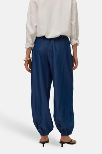 Blauwe broek van VERO MODA, met elastische tailleband en gerimpelde zoom, gecombineerd met een witte blouse en hakken.
