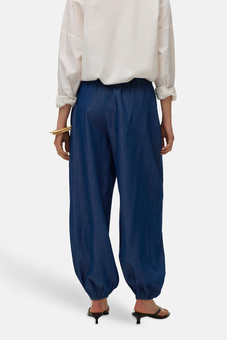Blauwe broek van VERO MODA, met elastische tailleband en gerimpelde zoom, gecombineerd met een witte blouse en hakken.
