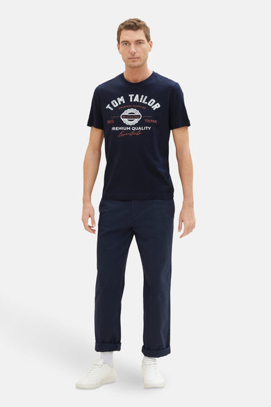 Blauw T-shirt van TOM TAILOR, met grafische print op de voorkant, gecombineerd met een donkerblauwe pantalon en witte sneakers.