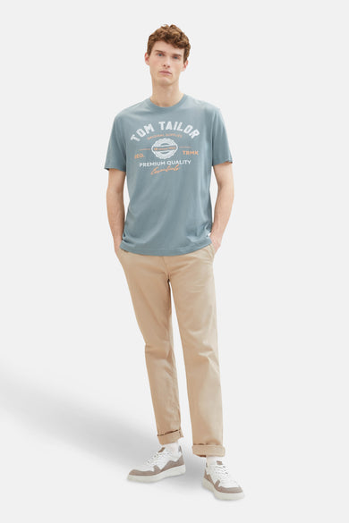 T-shirt bleu à manches courtes de TOM TAILOR, avec impression, porté avec un pantalon kaki et des baskets blanches.