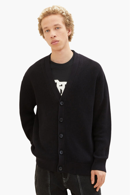Gilet noir de TOM TAILOR, porté sur un t-shirt noir imprimé et des jeans noirs.