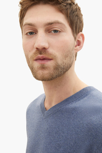 Man in blauwe V-hals trui.