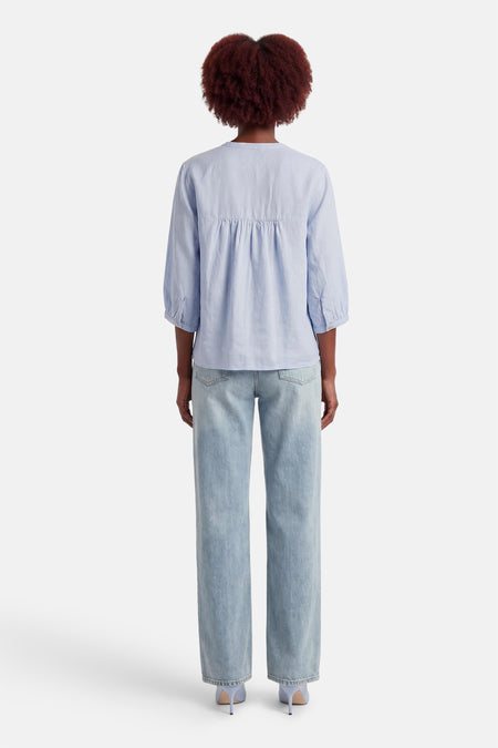 Chemise bleue à manches longues OPUS, associée à un jean ample et des talons bleus, vue de dos.