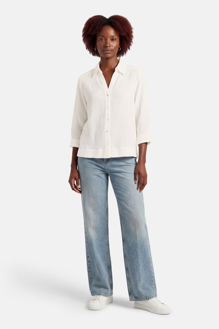 Chemise blanche à manches longues OPUS, avec un tissu texturé, portée avec un jean et des baskets blanches.