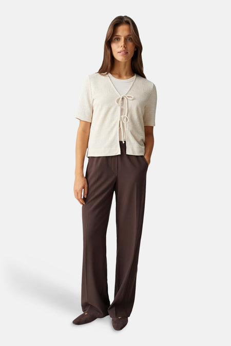 Beige blouse van OPUS, met korte mouwen en striksluiting, gedragen met bruine pantalon en schoenen.
