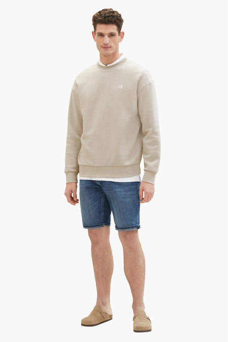 Jean en denim court dans le bleu marine, de TOM TAILOR, associé à un sweat-shirt beige et des mocassins en cuir.