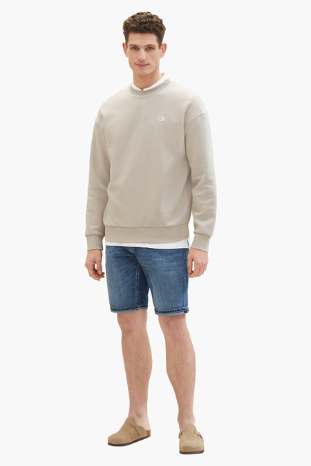 Jean court bleu marine de TOM TAILOR, porté avec un pull en coton beige et des mocassins en cuir.
